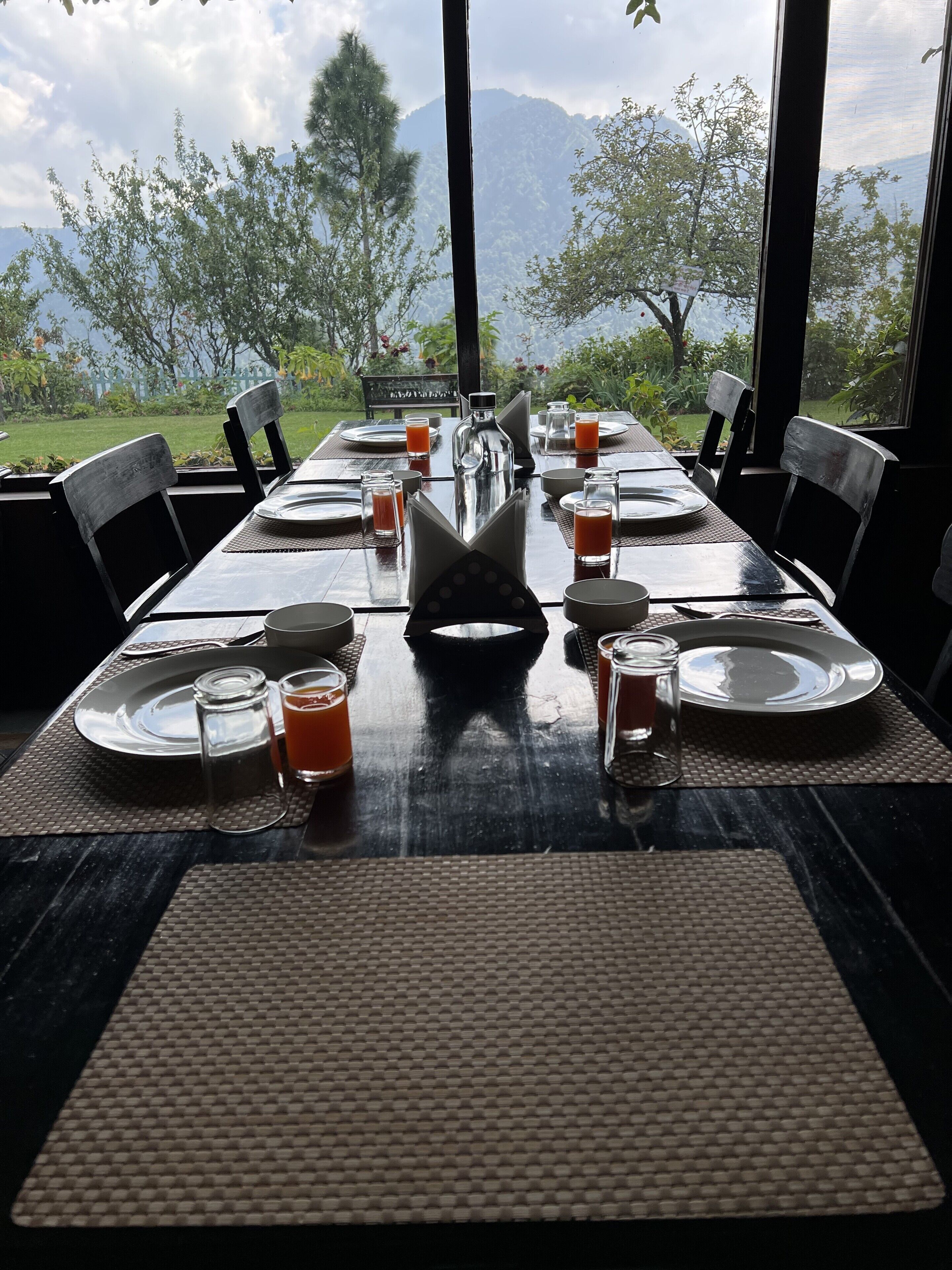 A dining table set for six with a view of mountains and trees.