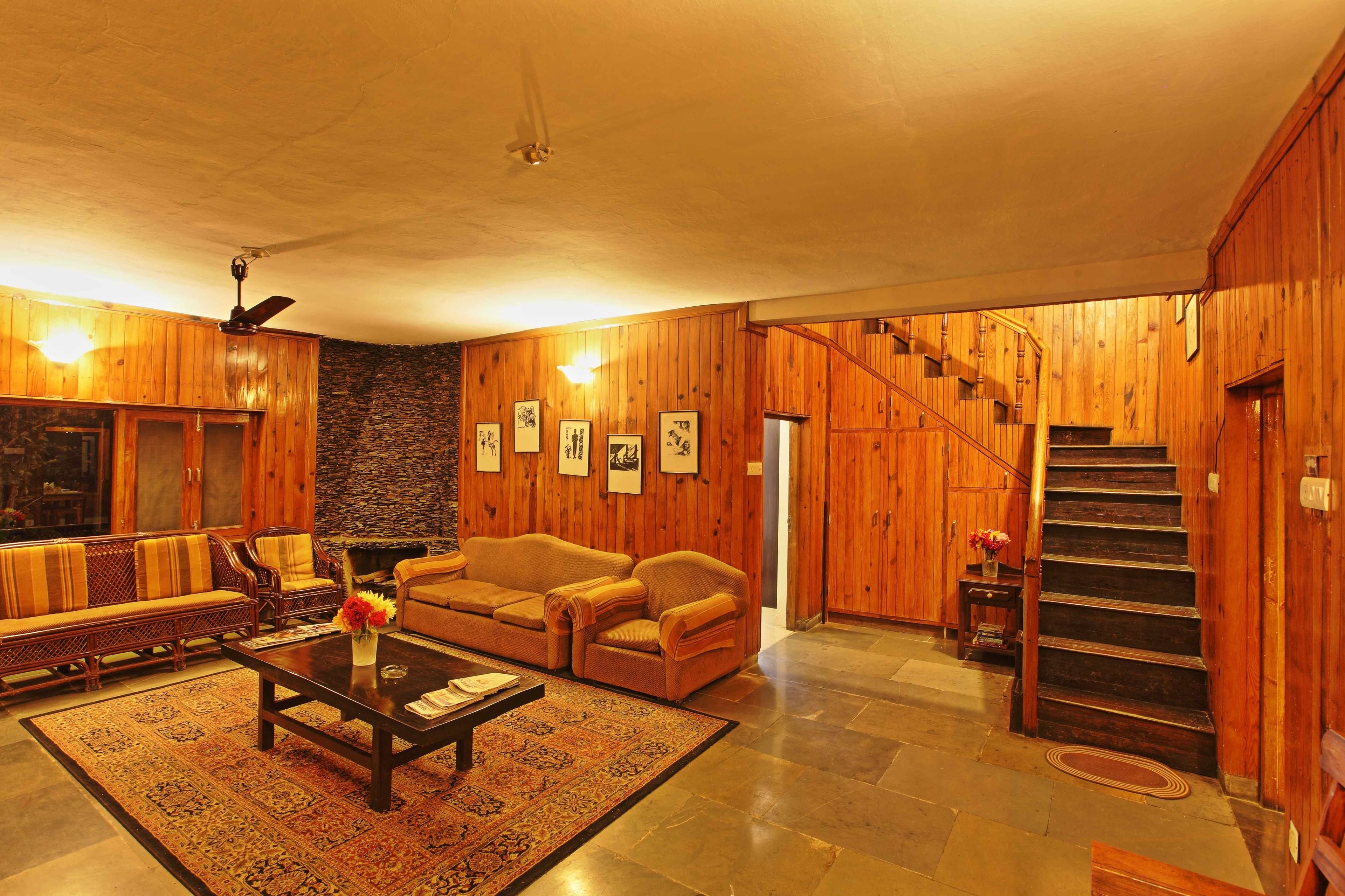 A wooden-finished living room with a sofa set, a coffee table, and a staircase.