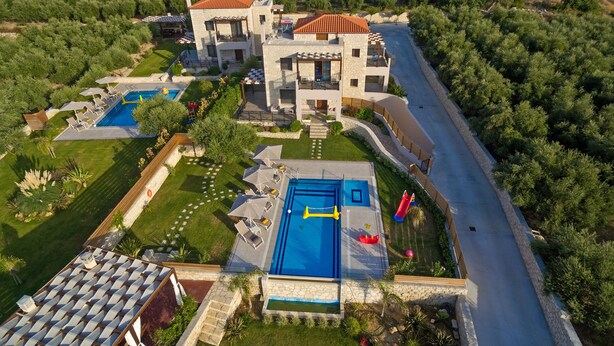 A large, modern villa with multiple swimming pools, surrounded by lush greenery and a scenic hillside view. - Olive Garden Villas (Mylopotamos)