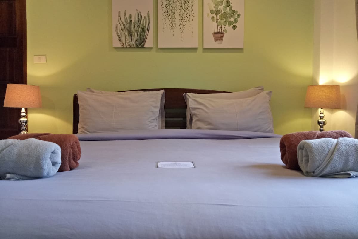 Habitación de hotel con cama, dos lámparas de noche y tres obras de arte colgadas en la pared.