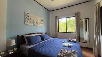 Habitación de hotel con una cama grande, una mesita de noche con lámpara, una ventana con cortinas y una obra de arte en la pared.