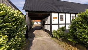 A narrow cobblestone path leading to a traditional half-timbered building with a sign indicating the number 16.