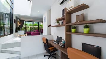 A modern office space with a desk, chair, and shelves with books and plants.