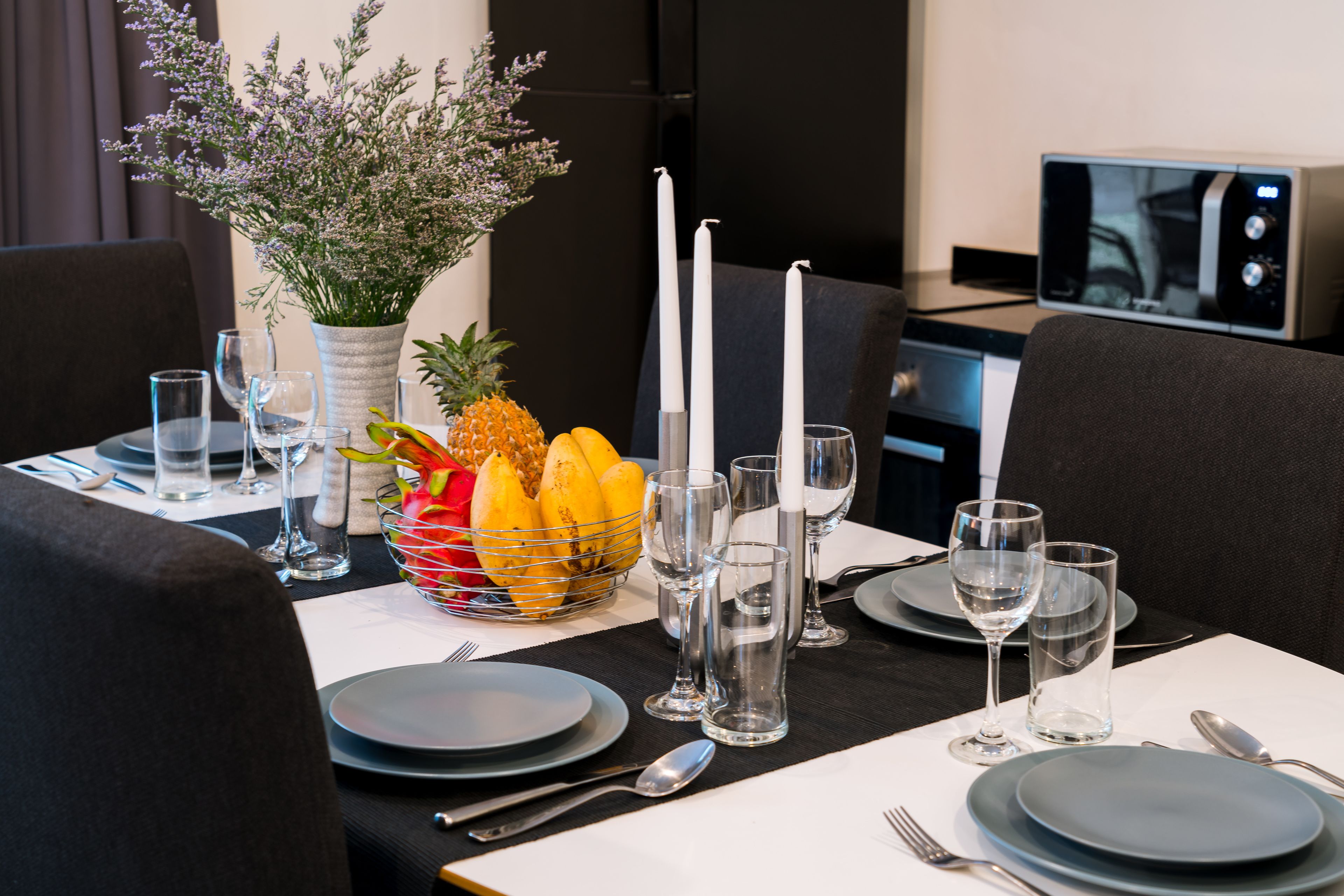 A dining table set with plates, cutlery, glasses, and a fruit bowl.