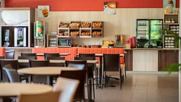 Ein Restaurant mit Sitzecken und Tischen, einer Kaffeemaschine und einer Auswahl an Gebäck.