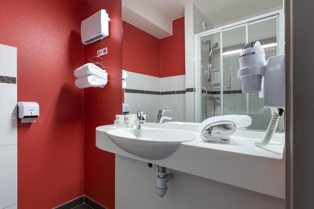 A bathroom with a white sink, a mirror, a towel rack, and a hairdryer.