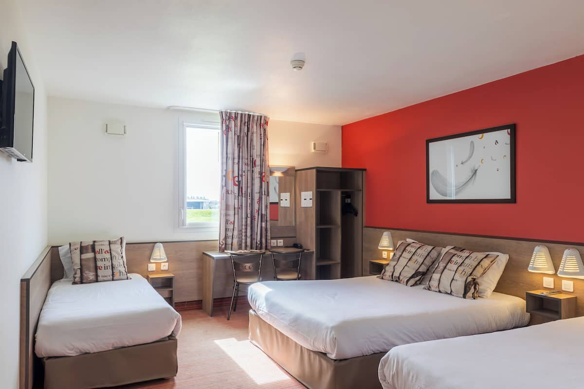 Quarto de hotel com duas camas, uma escrivaninha, uma cadeira, um guarda-roupa e uma janela com cortinas.