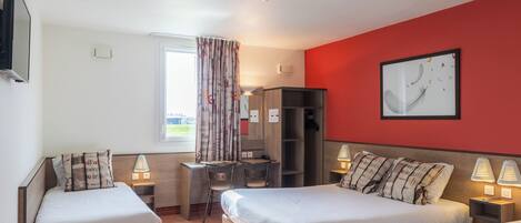 Habitación de hotel con dos camas, un escritorio, una silla, un armario y una pared roja decorativa.