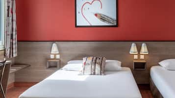 A hotel room with a large bed, two bedside tables with lamps, a headboard, and a wall with a framed picture.