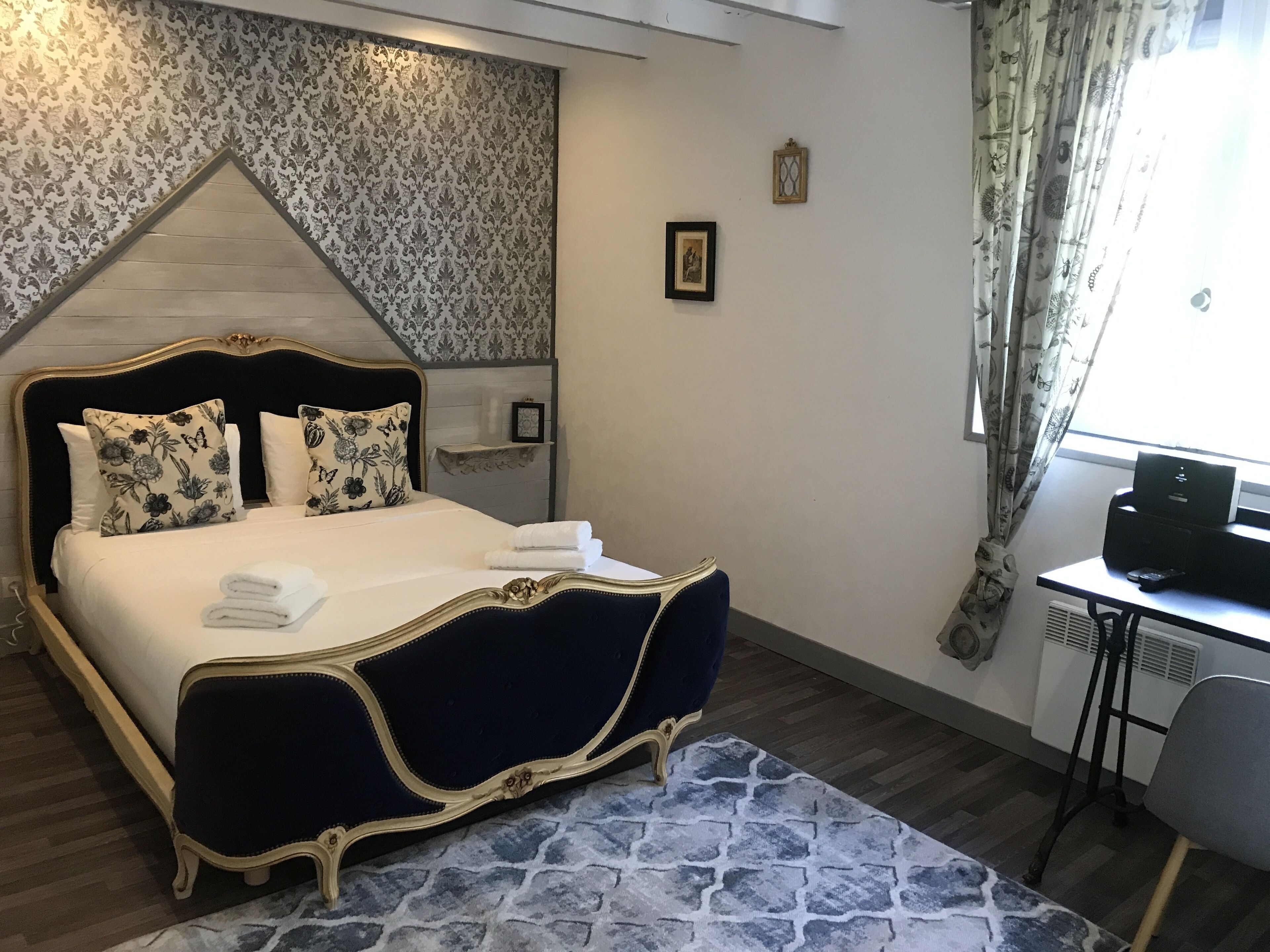Een slaapkamer met een groot bed, een bureau en een stoel.