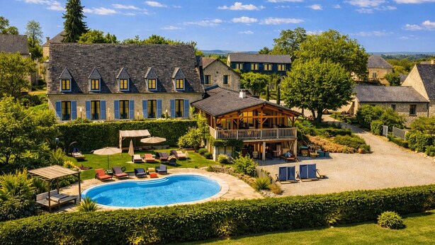 A large building with multiple windows and a swimming pool. - Hôtel Bien-Etre Aux Cyprès de Marquay (Marquay)
