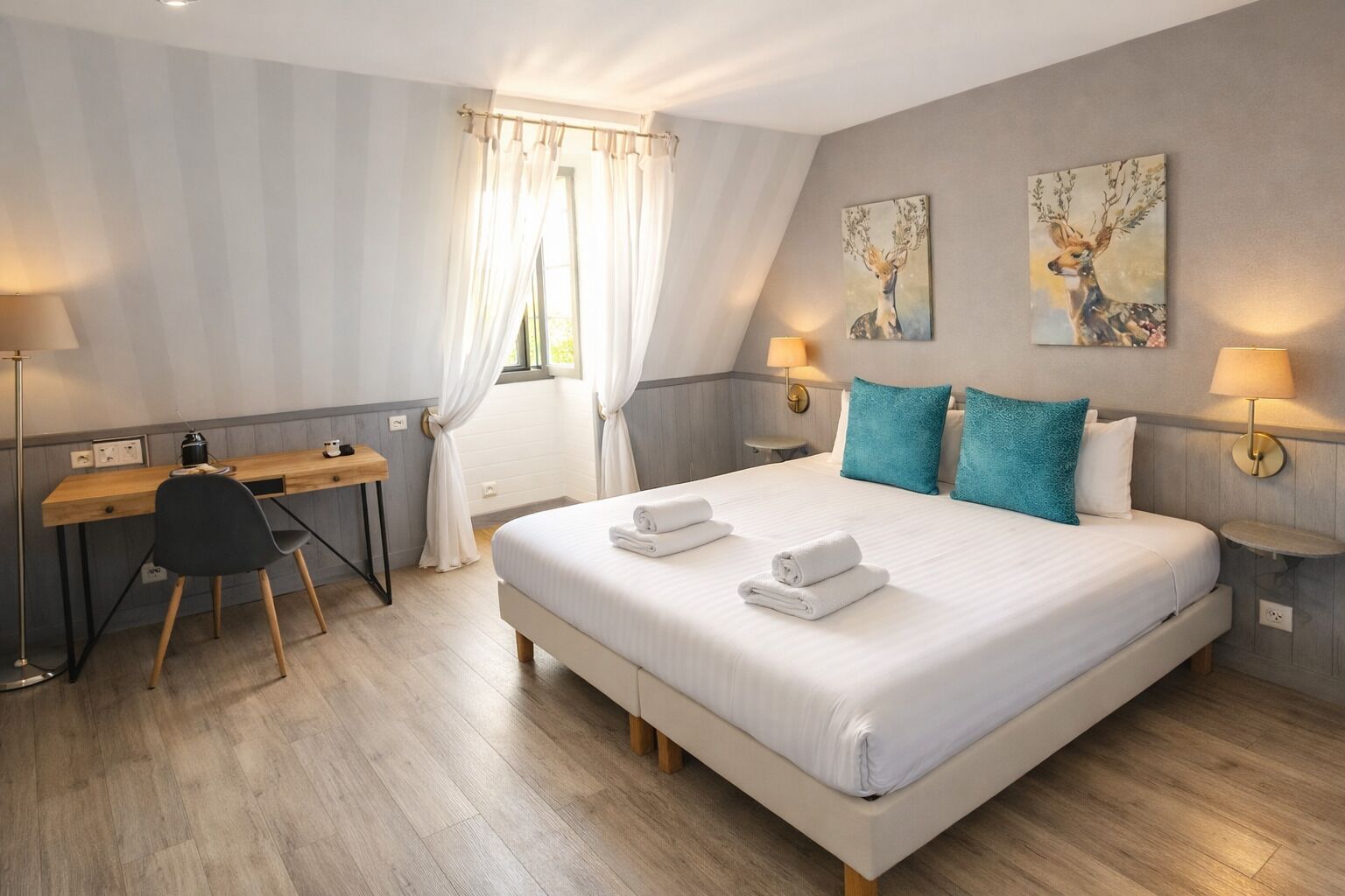 A bedroom with a bed, a desk, and two paintings on the wall.