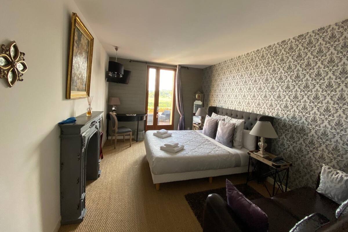 Une chambre d’hôtel équipée d’un lit, d’un bureau, d’une chaise, d’une télévision et offrant une vue sur l’extérieur.