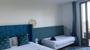 A hotel room with two beds, a decorative wall piece, and a view through a glass door.
