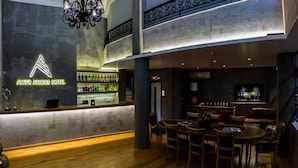 Un hall d’hôtel moderne avec un bar, des meubles en bois et un lustre.