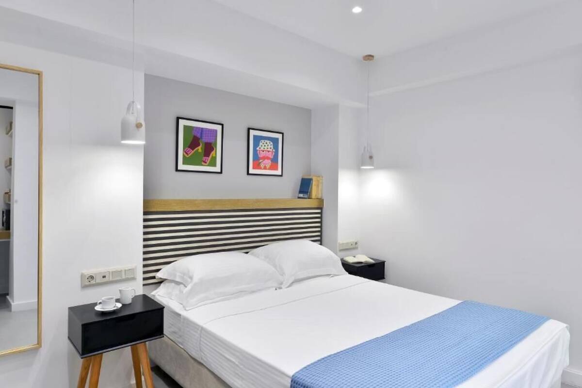 A modern hotel room with a bed, bedside tables, and artwork on the wall.