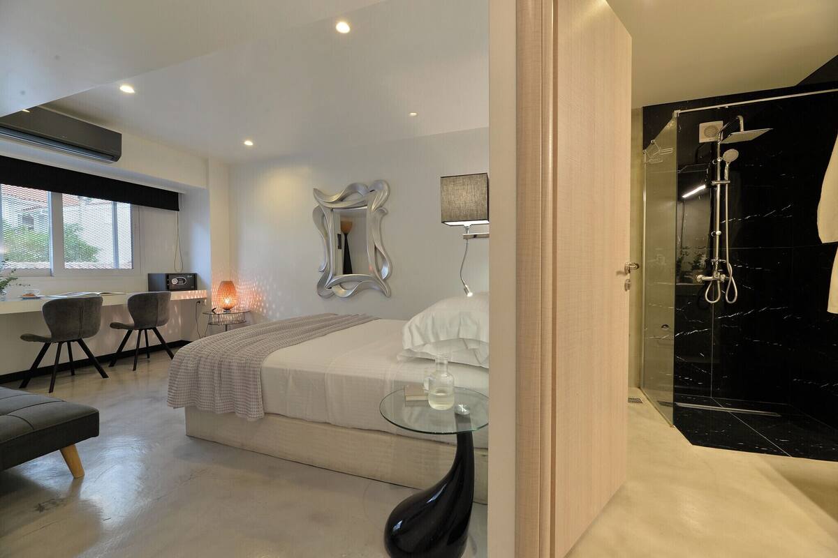 A modern bedroom with a bed, bedside table, and a glass-enclosed shower.