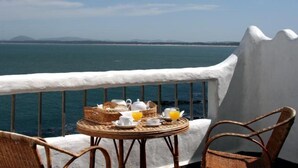 Un balcón con una mesa lista para el desayuno y vista a un cuerpo de agua.