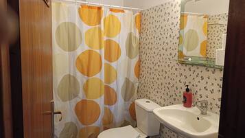 A bathroom with a toilet, sink, shower curtain with circular patterns, and a mirror above the sink.