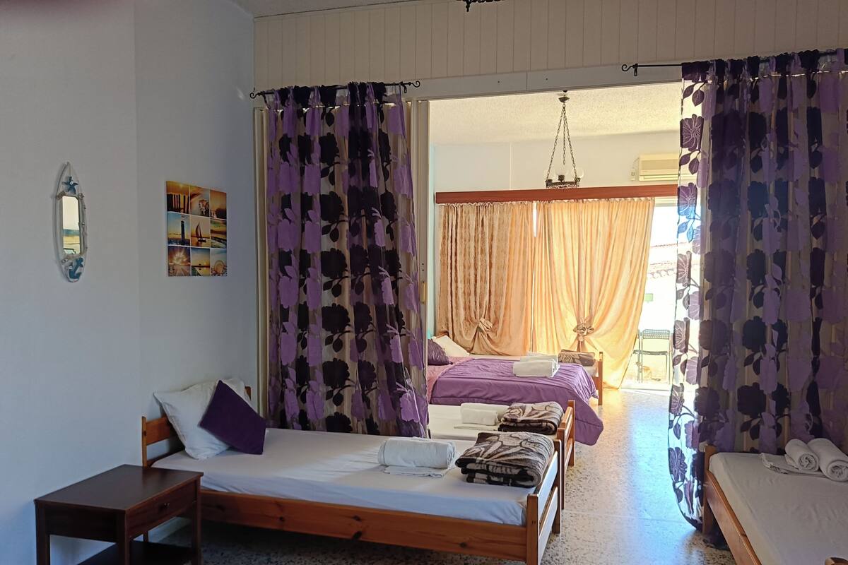 Un dormitorio con cama, escritorio y silla. Hay cortinas y una ventana.