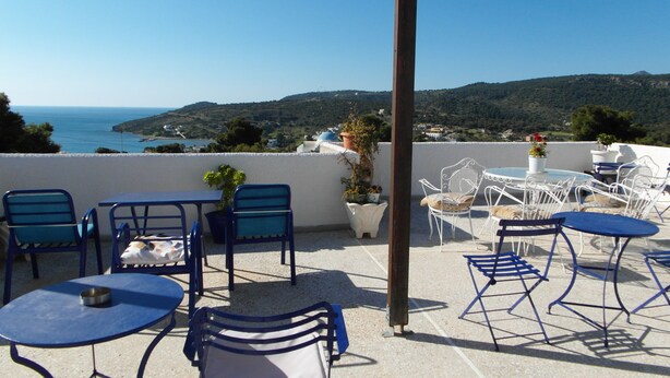 Una terraza con mobiliario exterior, vista al mar y un paisaje montañoso.