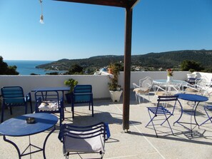 A terrace with outdoor seating, a view of the sea, and a mountainous landscape. - Eri Studios (Aegina)