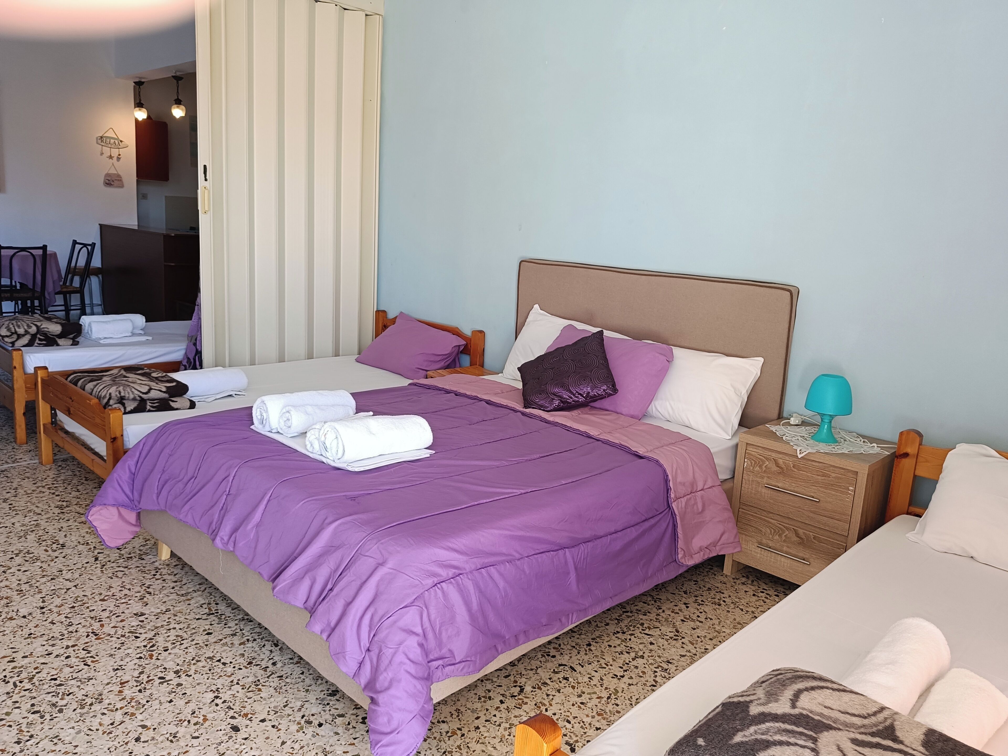 A hotel room with two beds, a wooden nightstand, a lamp, and a bathroom visible through an open door.