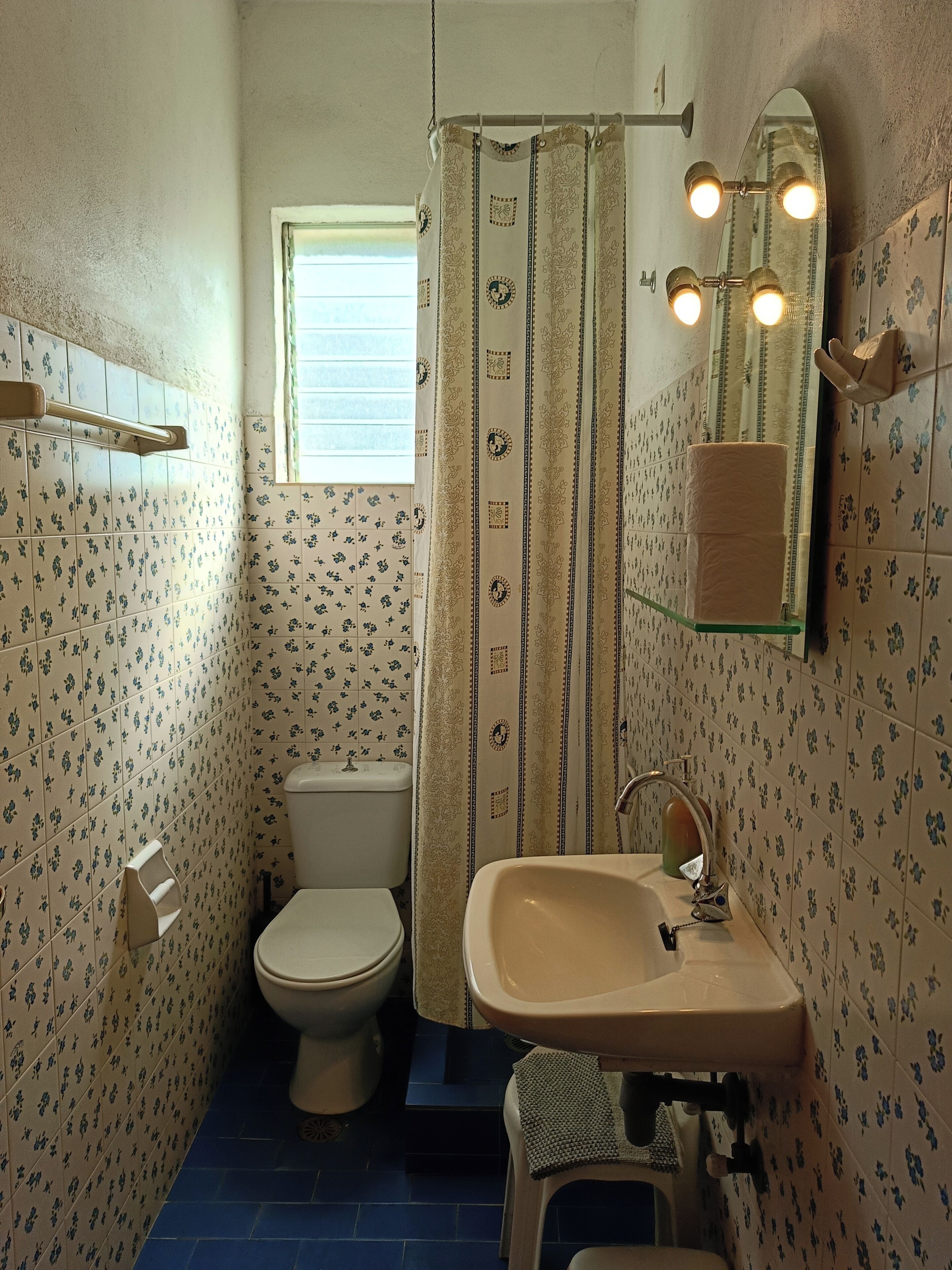 Une salle de bain avec des toilettes, un lavabo et un rideau de douche.