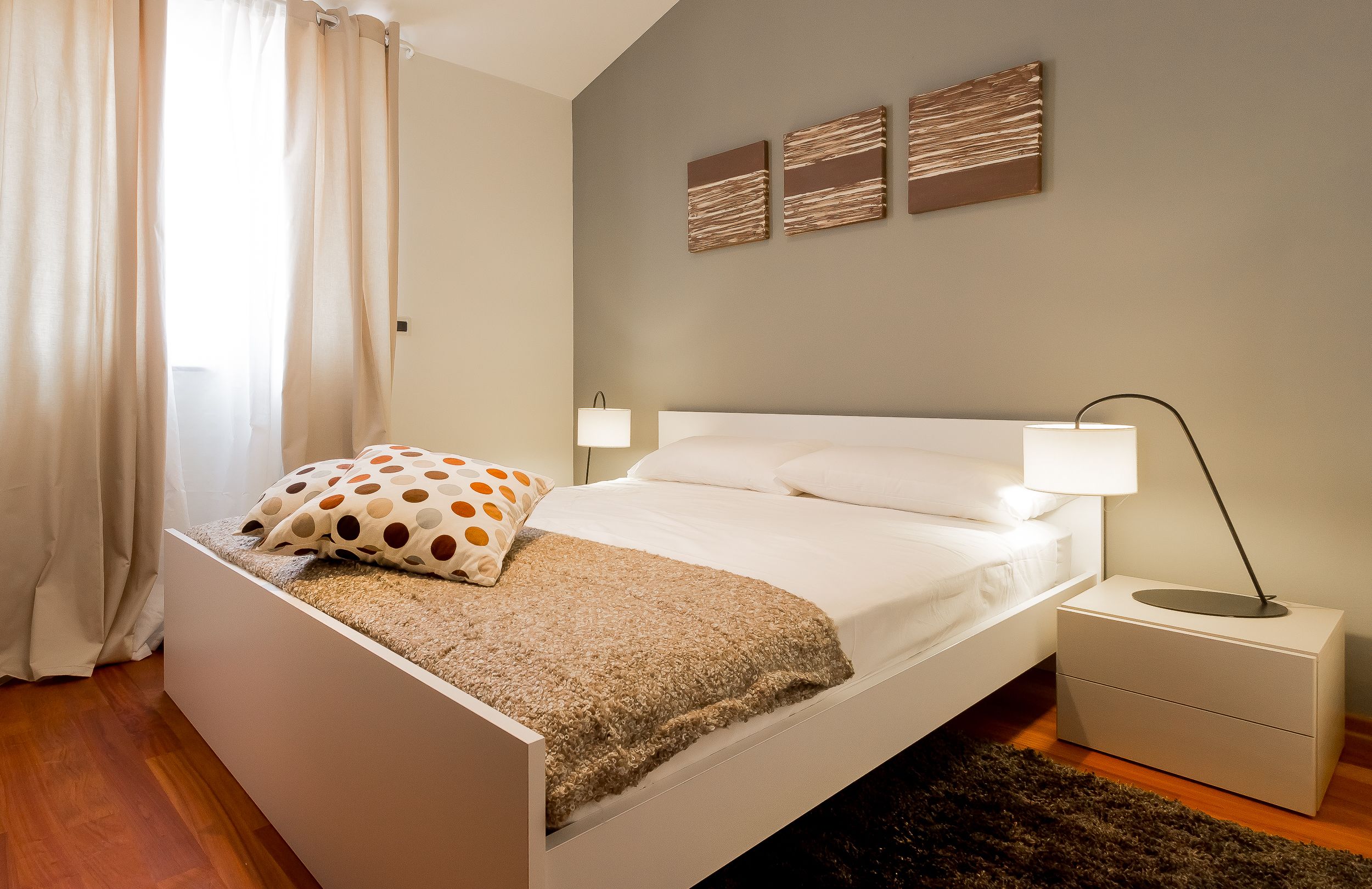 A neatly arranged bedroom with a bed, bedside tables, and a window with curtains.