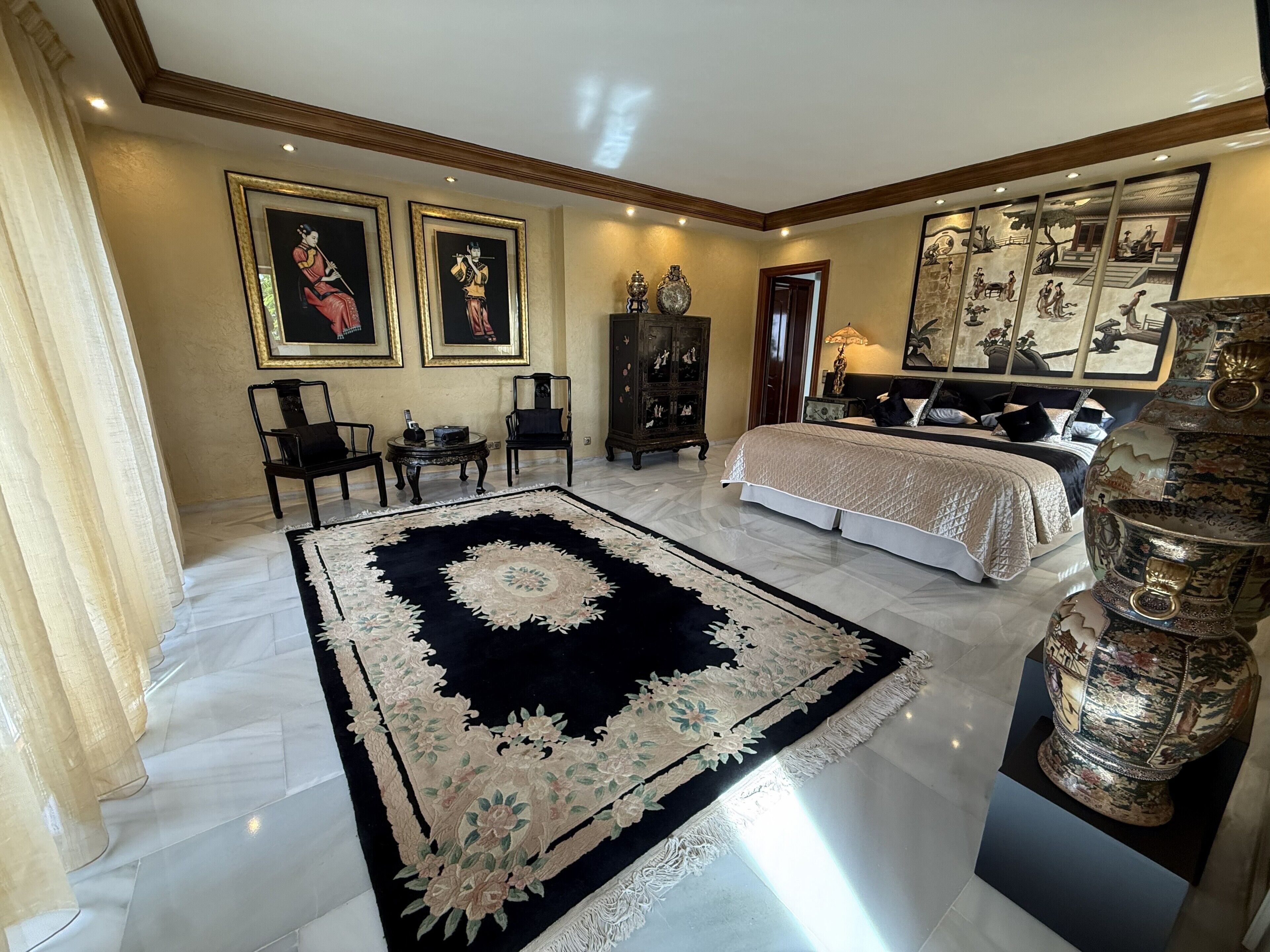 A spacious bedroom with a large bed, a decorative rug, and artwork on the walls.
