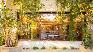 A modern building with large windows, indoor plants, and a well-maintained lawn. - Villa Turrión (Marbella)