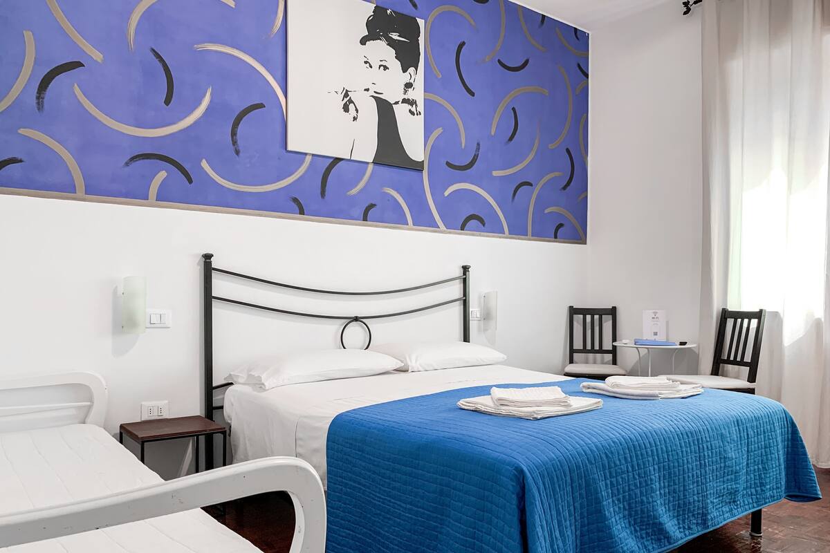 A hotel room with a bed, a desk, and a chair.