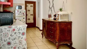 A kitchen with a microwave, toaster, and a refrigerator. There is a wooden cabinet and a wall with a silhouette of a dancing figure. - Ariel B&B (Verona)