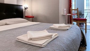 A hotel room with a large bed, a nightstand, a red wall decoration, a mirror, and a view of the outside. - Ariel B&B (Verona)