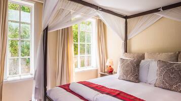 A bedroom with a large bed, a nightstand, a lamp, and a window with curtains.