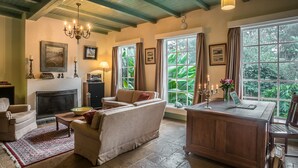 Una sala de estar acogedora con chimenea, un sofá, una mesa de centro y un escritorio de madera con una computadora portátil.