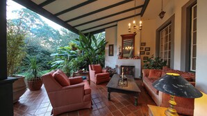 Un espacio de sala acogedor con chimenea, asientos cómodos y vistas a vegetación exuberante.