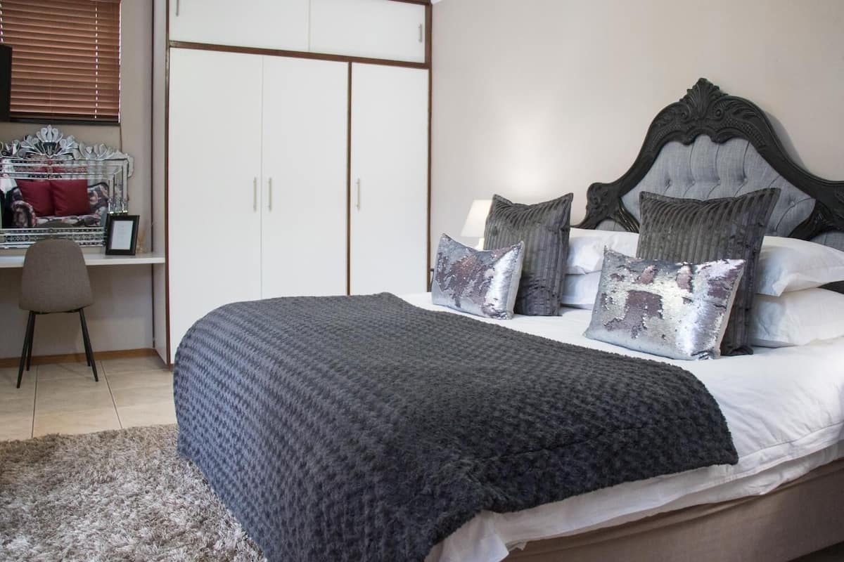 A bedroom with a large bed, a desk with a chair, and a wardrobe.
