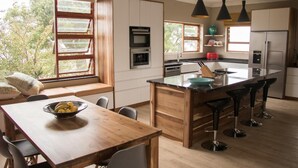 A modern kitchen with a wooden island, bar stools, and a dining table with chairs. - A Queenslin Guesthouse (Paarl)
