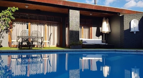 Una piscina al aire libre, sillones reclinables de piscina