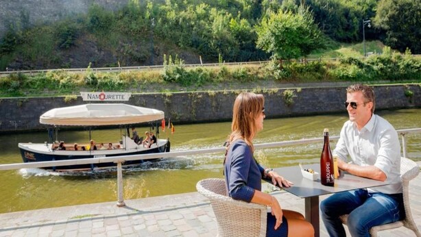 A boat with 'NOMOURETTE' on its side docked at a riverside café. - Holiday Home in Gedinne by the River (Vencimont)