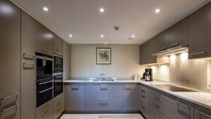 A modern kitchen with built-in appliances, a central island, and a granite countertop. - Holiday Home in Gedinne by the River (Vencimont)
