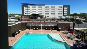 A hotel with a swimming pool, outdoor seating, and a view of the parking area. - Home2 Suites by Hilton McAllen (McAllen)