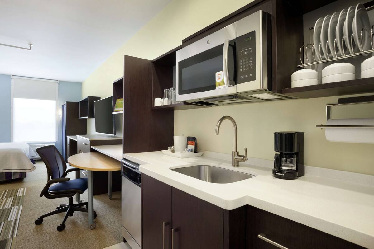 A modern kitchen with a microwave, coffee maker, and sink.