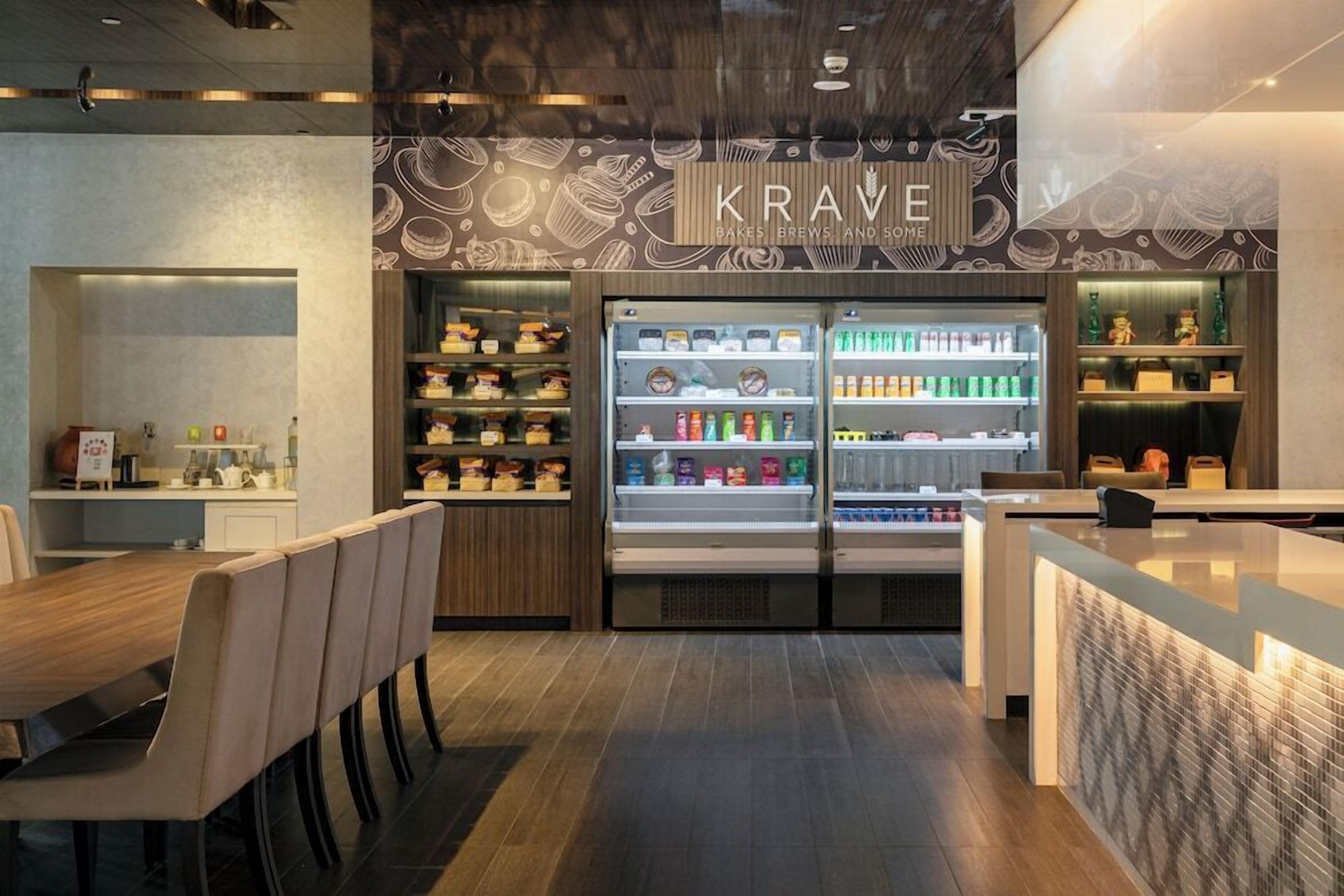 A modern interior with a dining area, a bakery display, and a counter with a menu.