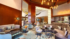 A spacious lobby with a large seating area, a bar, and a view of the kitchen. - Radisson Blu Jammu (Jammu)