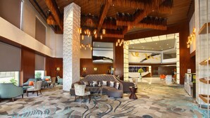 A spacious lobby with a large sofa, multiple chairs, a patterned carpet, and a modern chandelier. - Radisson Blu Jammu (Jammu)