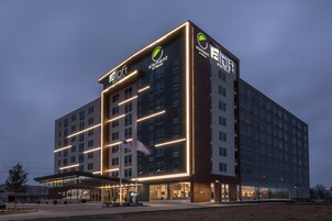 Et moderne hotel med et tydeligt logo, flere etager og en godt oplyst indgang.