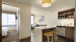 A modern kitchen with a central island, bar stools, and a microwave. - Element by Marriott Dallas Love Field (Dallas)