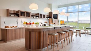 A modern kitchen with a central island, bar stools, and a large window offering a view of the outdoors. - Element by Marriott Dallas Love Field (Dallas)